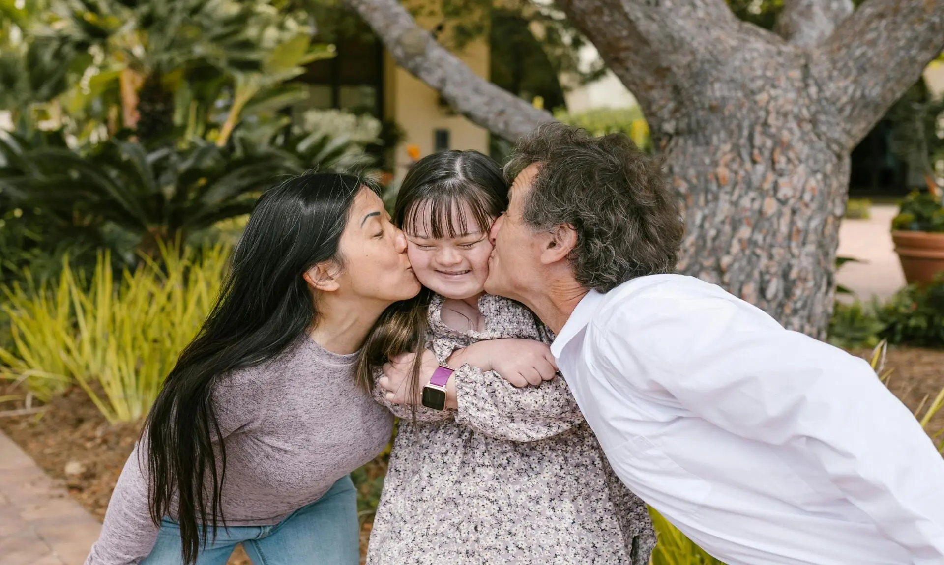 Loving parents tenderly kissing their autistic daughter, showing affection and care.